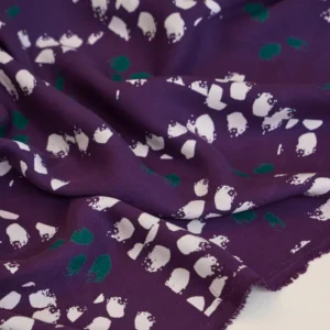 Textura tejido sarga Tencel morado detalle estampado manchitas y brillo semimate.