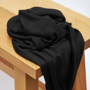 Tela de Punto Soft Lima Knit en color negro profundo, dispuesta en pliegues suaves para mostrar su textura elegante y caída pesada.