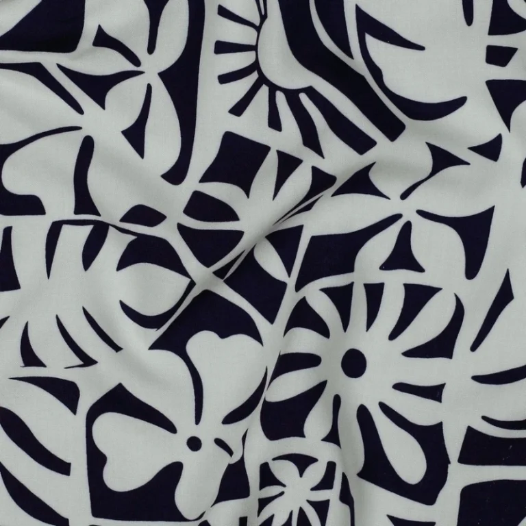 tela de viscosa 100 % Ecovero™ doblada mostrando el derecho y el revés del tejido, con un original estampado de estilo tropical en azul marino y blanco que incluye hojas de monstera y motivos solares.